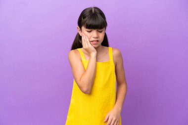 Little caucasian kid isolated on purple background with toothache