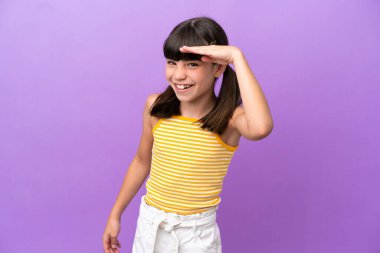 Küçük beyaz çocuk, mor arka planda izole edilmiş. Bir şeye bakmak için uzaklara bakıyor.