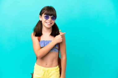 Küçük beyaz bir çocuk kumsala gidiyor. Mavi arka planda izole edilmiş bir şekilde. Yan tarafı göstererek bir ürün sunuyor.