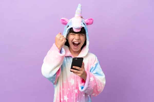 Little Kid Wearing Unicorn Pajama Isolated Purple Background Phone Victory — Zdjęcie stockowe