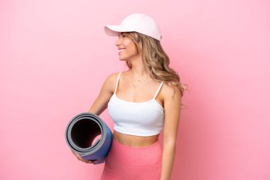 Young sport woman going to yoga classes while holding a mat looking side