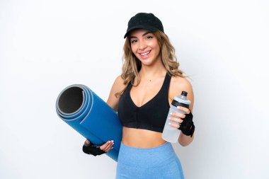 Beyaz arka planda izole edilmiş beyaz tenli genç bir kadın spor su şişesi ve bir paspas ile