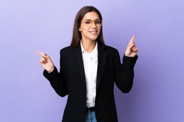 Business woman isolated on purple background pointing finger to the laterals and happy