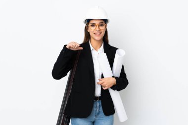 Young architect caucasian woman with helmet and holding blueprints over isolated background proud and self-satisfied
