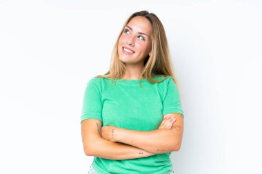 Beyaz arka planda izole edilmiş genç beyaz kadın gülümserken yukarı bakıyor.