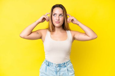 Sarı arka planda izole edilmiş beyaz bir kadın. Şüpheleri ve düşünceleri var.