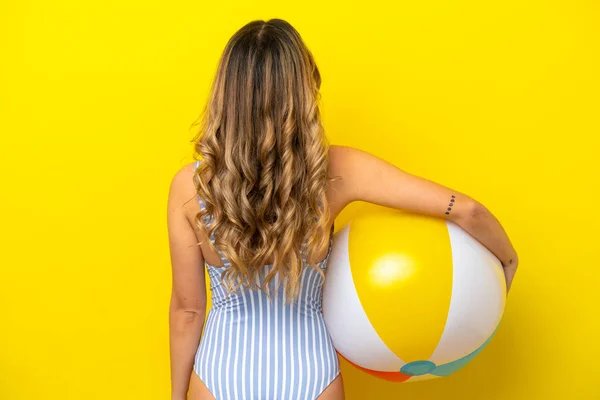 Young Woman Holding Beach Ball Isolated Yellow Background Back Position — ストック写真