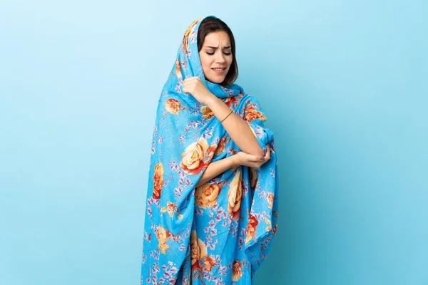 Young Moroccan woman with traditional costume isolated on blue background with pain in elbow