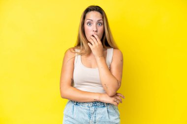 Sarı arka planda izole edilmiş genç beyaz kadın sağa bakarken şaşırdı ve şok oldu.