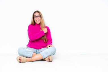 Beyaz arka planda izole bir şekilde yerde oturan beyaz bir kadın zaferi kutluyor.