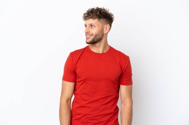 Beyaz arka planda soyutlanmış beyaz tenli yakışıklı bir adam yan tarafa bakıyor ve gülümsüyor.