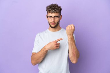 Delivery caucasian man isolated on purple background making the gesture of being late