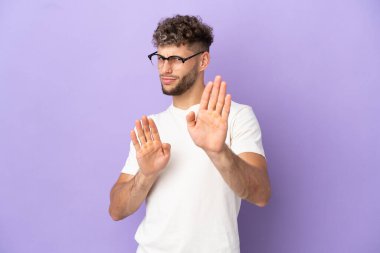 Delivery caucasian man isolated on purple background nervous stretching hands to the front