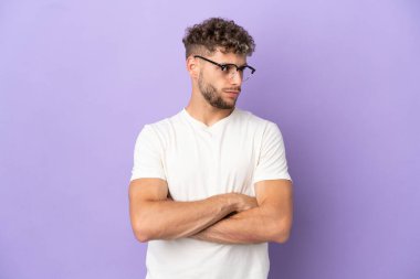 Delivery caucasian man isolated on purple background keeping the arms crossed