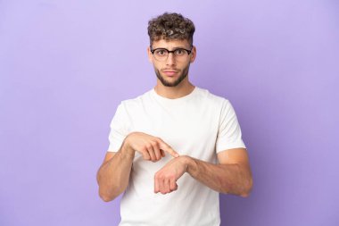 Delivery caucasian man isolated on purple background making the gesture of being late