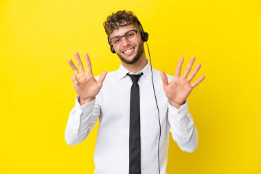 Telemarketer blonde man working with a headset isolated on yellow background counting nine with fingers