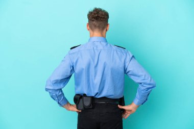 Young police blonde man isolated white on blue background in back position