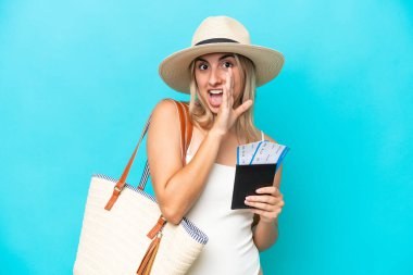 Young caucasian woman in swimsuit holding a passport isolated on blue background whispering something