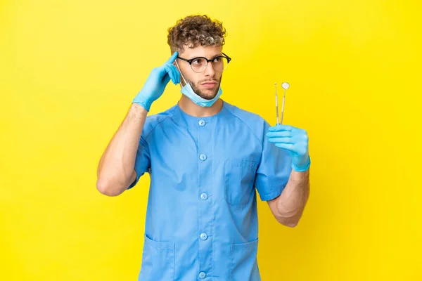 Dentist Blonde Man Holding Tools Isolated Background Having Doubts Thinking — Fotografia de Stock
