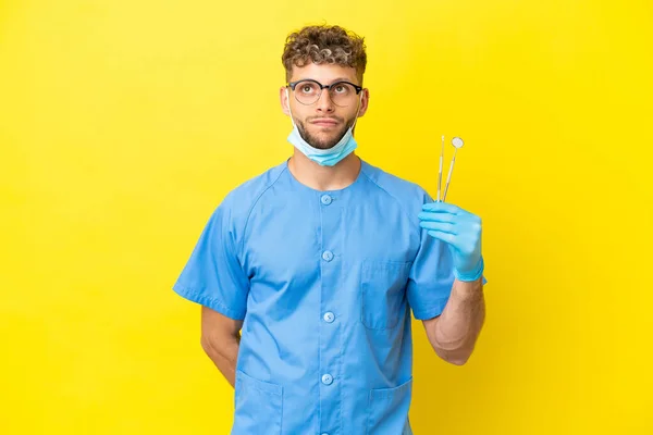 Dentist Blonde Man Holding Tools Isolated Background Looking — Zdjęcie stockowe