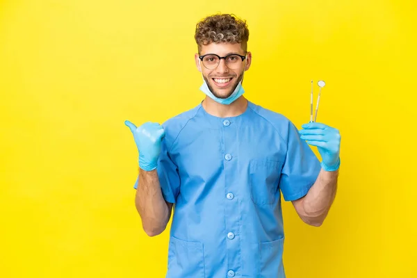 Dentist Blonde Man Holding Tools Isolated Background Pointing Side Present — Fotografia de Stock