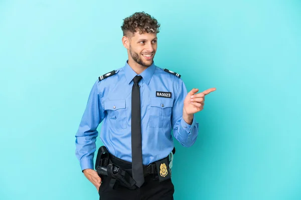 Young police blonde man isolated white on blue background pointing finger to the side and presenting a product