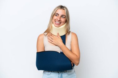Woman with broken arm and wearing a sling isolated on white background looking up while smiling