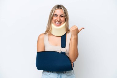 Woman with broken arm and wearing a sling isolated on white background pointing to the side to present a product