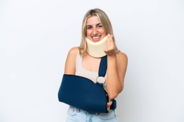 Woman with broken arm and wearing a sling isolated on white background making money gesture