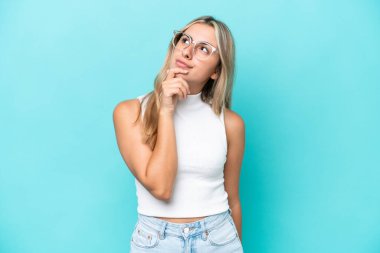 Genç beyaz kadın mavi arka planda izole edilmiş ve yukarı bakıyor.