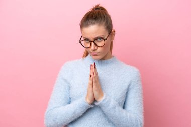 Pembe arka planda izole edilmiş genç beyaz kadın avuç içlerini bir arada tutuyor. İnsan bir şey ister.