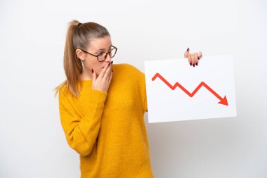 Young caucasian woman isolated on white background holding a sign with a decreasing statistics arrow symbol with surprised expression