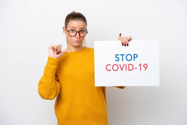 Young caucasian woman isolated on white background holding a placard with text Stop Covid 19 with proud gesture