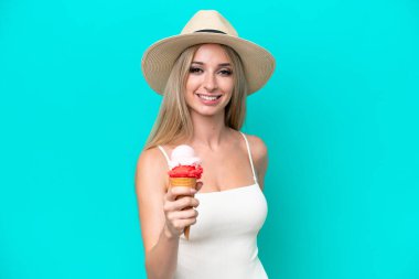 Mayo giymiş sarışın bir kadın elinde dondurmayla mavi arka planda mutlu bir ifadeyle izole edilmiş.