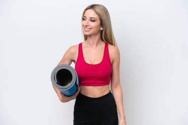 Genç sarışın kadın yoga derslerine giderken beyaz arka planda izole edilmiş bir minder tutuyor.