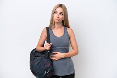 Young sport woman with sport bag isolated on white background making doubts gesture while lifting the shoulders