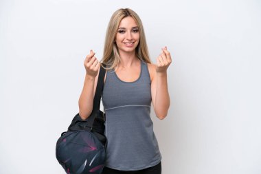Spor çantalı genç bir kadın beyaz arka planda izole edilmiş para hareketi yapıyor.