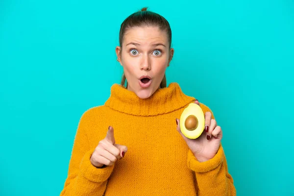 Young Caucasian Woman Holding Avocado Isolated Blue Background Surprised Pointing — Foto Stock