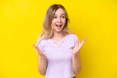 Blonde English young girl isolated on yellow background with surprise facial expression