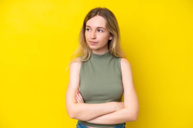 Blonde English young girl isolated on yellow background keeping the arms crossed