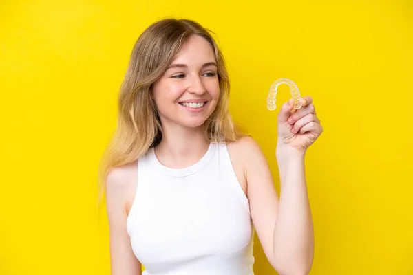 Blonde English Young Girl Holding Invisible Braces Isolated Yellow Background — Stock fotografie