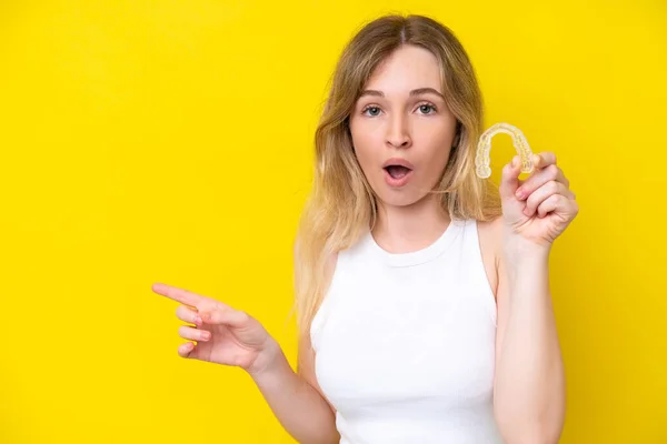 Blonde English Young Girl Holding Invisible Braces Isolated Yellow Background — Fotografia de Stock