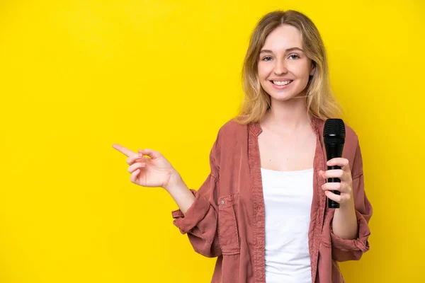 Young Singer Caucasian Woman Picking Microphone Isolated Yellow Background Pointing — Stok fotoğraf
