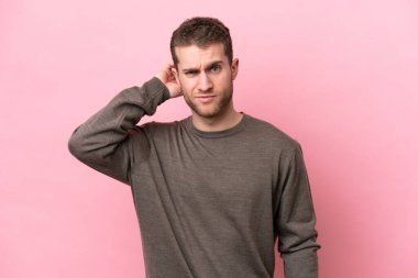 Pembe arka planda izole edilmiş genç beyaz adamın şüpheleri var.