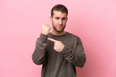 Pembe arka planda izole genç beyaz adam geç kalma jesti yapıyor.