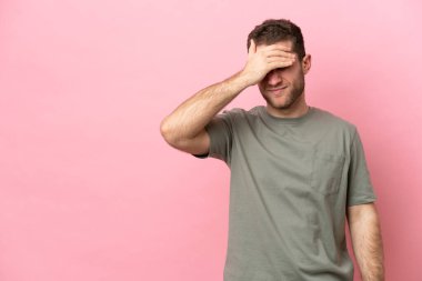 Kafkasyalı genç adam pembe arka planda izole edilmiş, baş ağrısı var.