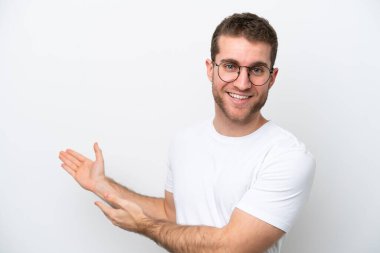 Young caucasian man isolated on white background With glasses and presenting something