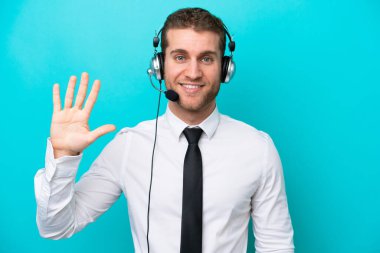 Telemarketer caucasian man working with a headset isolated on blue background counting five with fingers