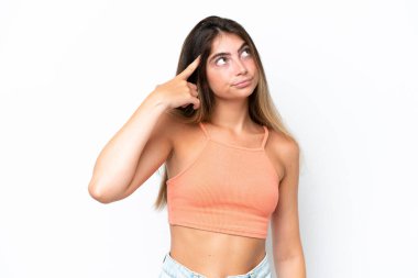 Beyaz arka planda soyutlanmış genç beyaz bir kadın deliliğin jestini yapıyor. Parmağını kafaya koyuyor.