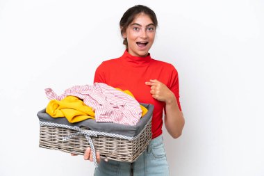 Young caucasian woman holding a clothes basket isolated on white background with surprise facial expression